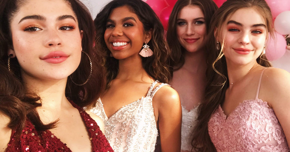 Close up of four teens in different prom dress styles against a balloon backdrop.