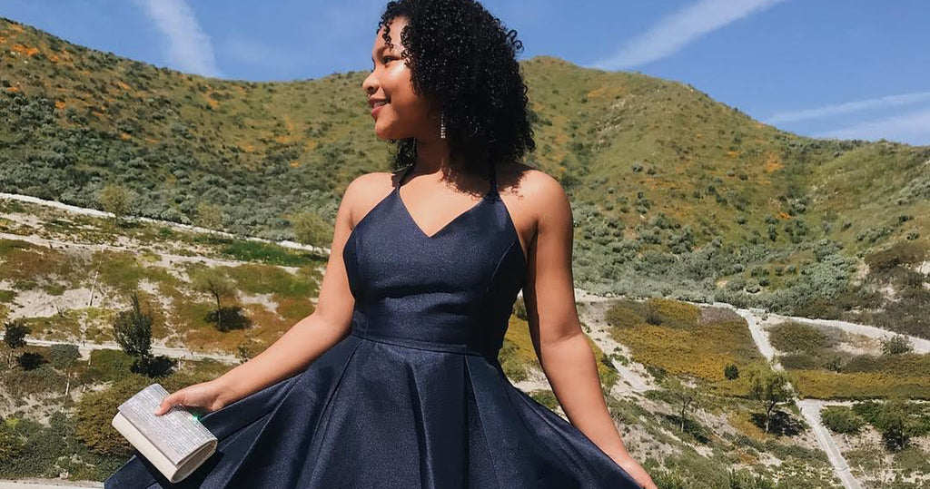 Teen girl wearing a simple satin short junior prom dress against a mountain backdrop.