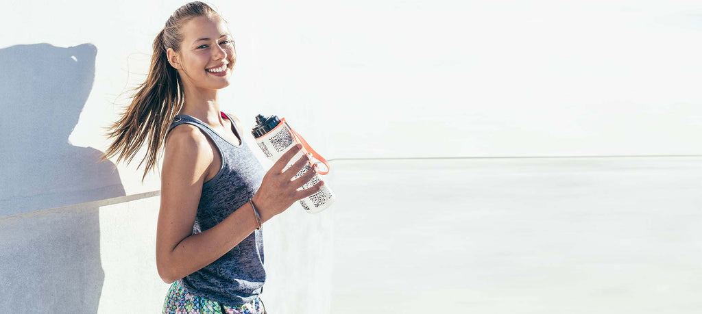 Smiling teen girl in workout clothes ready to drink water, a health and fitness tip for prom prep.