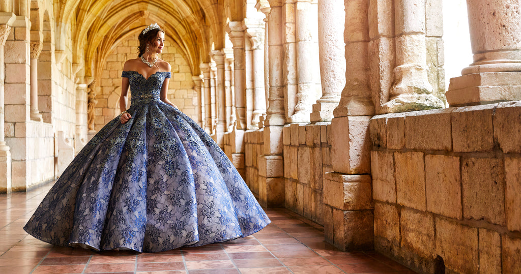 Teen girl wearing an off-the-shoulder navy blue lace quince ball gown.