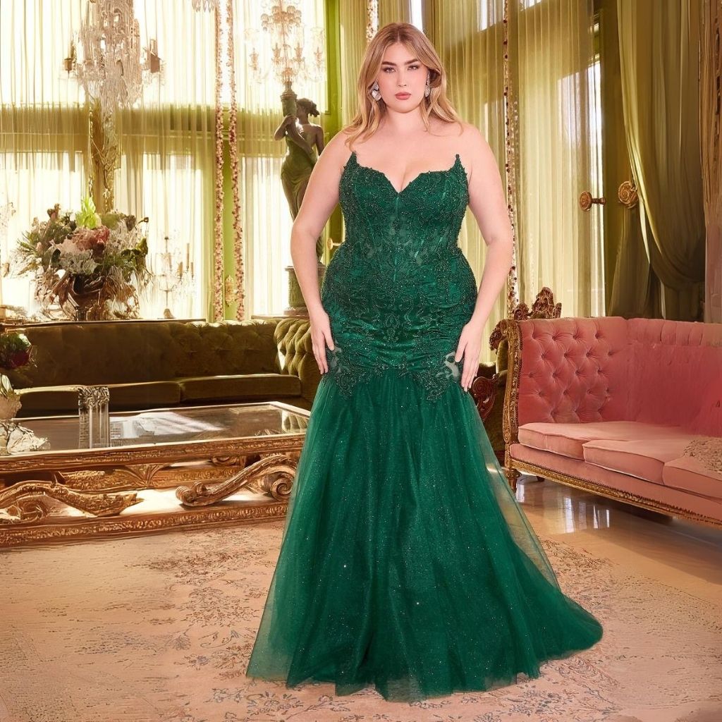 Wearing an emerald green plus-size embroidered formal dress, a woman stands in an in ornate parlor.