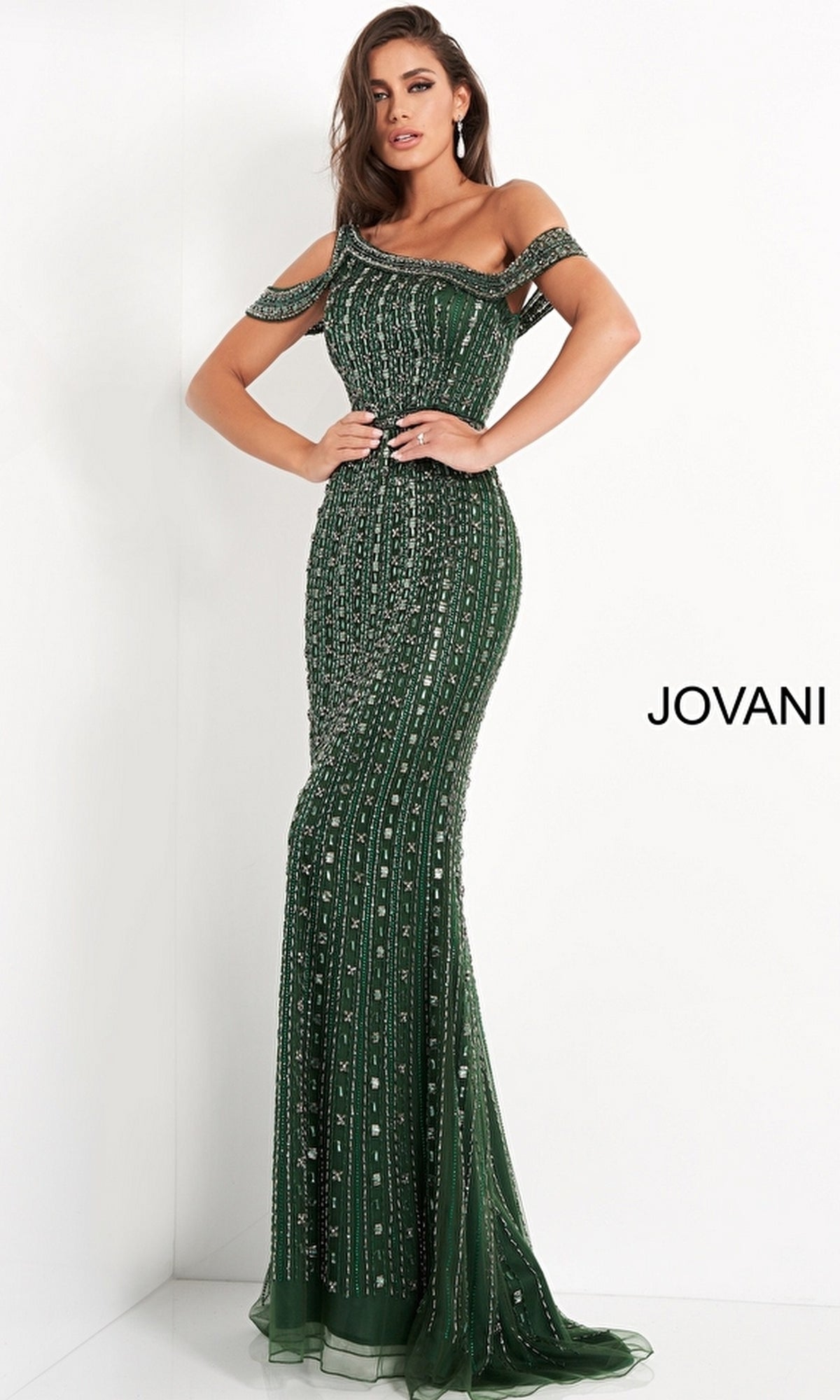 A woman in the Jovani Asymmetrical Beaded Long Formal Dress 03124—an off-the-shoulder, floor-length dark green gown—stands against a white background with