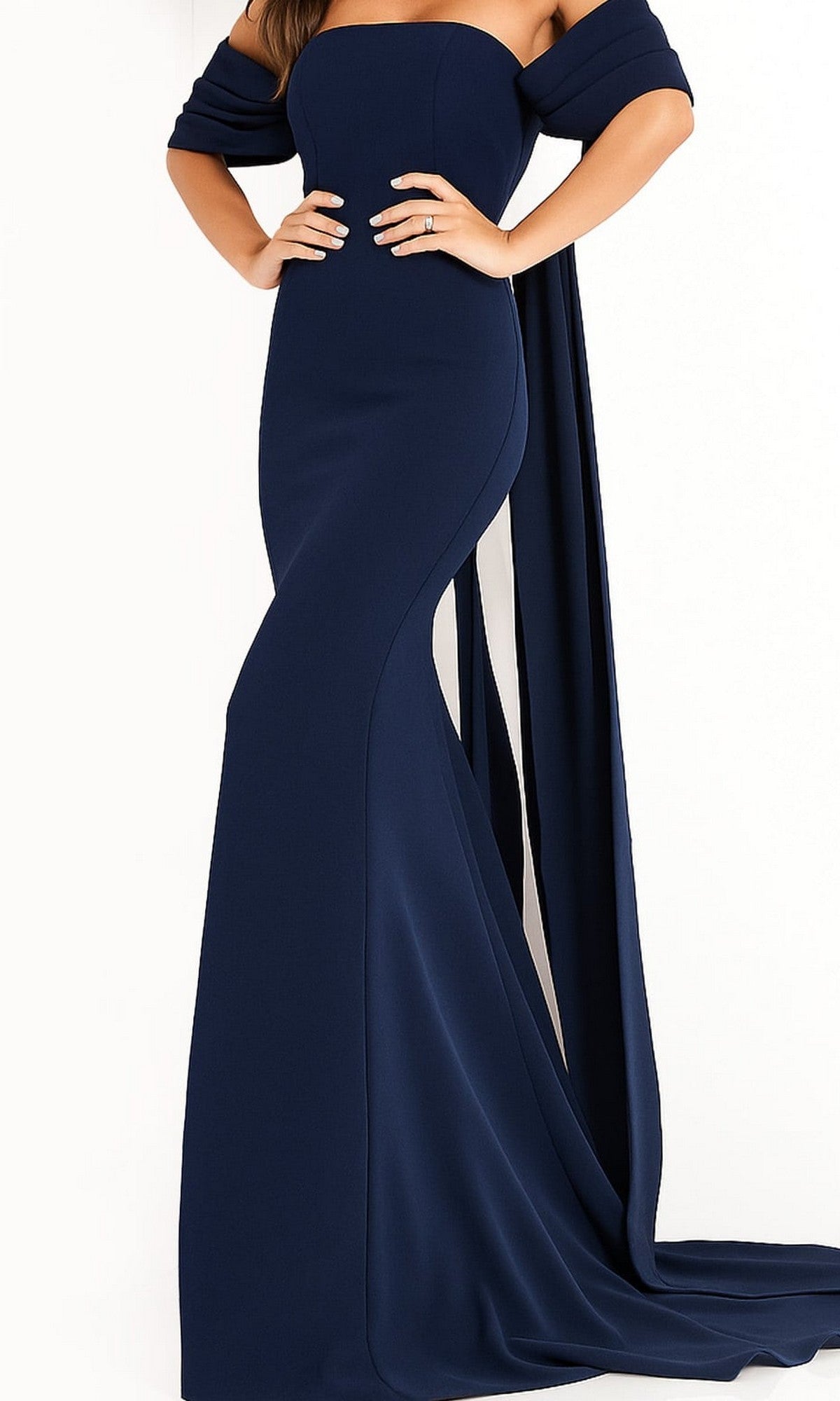A woman poses with her hands on her hips against a plain white background, wearing the Jovani 04350 Long Prom Dress—a fitted, strapless floor-length gown in navy crepe with elegant off-the-shoulder drapes.