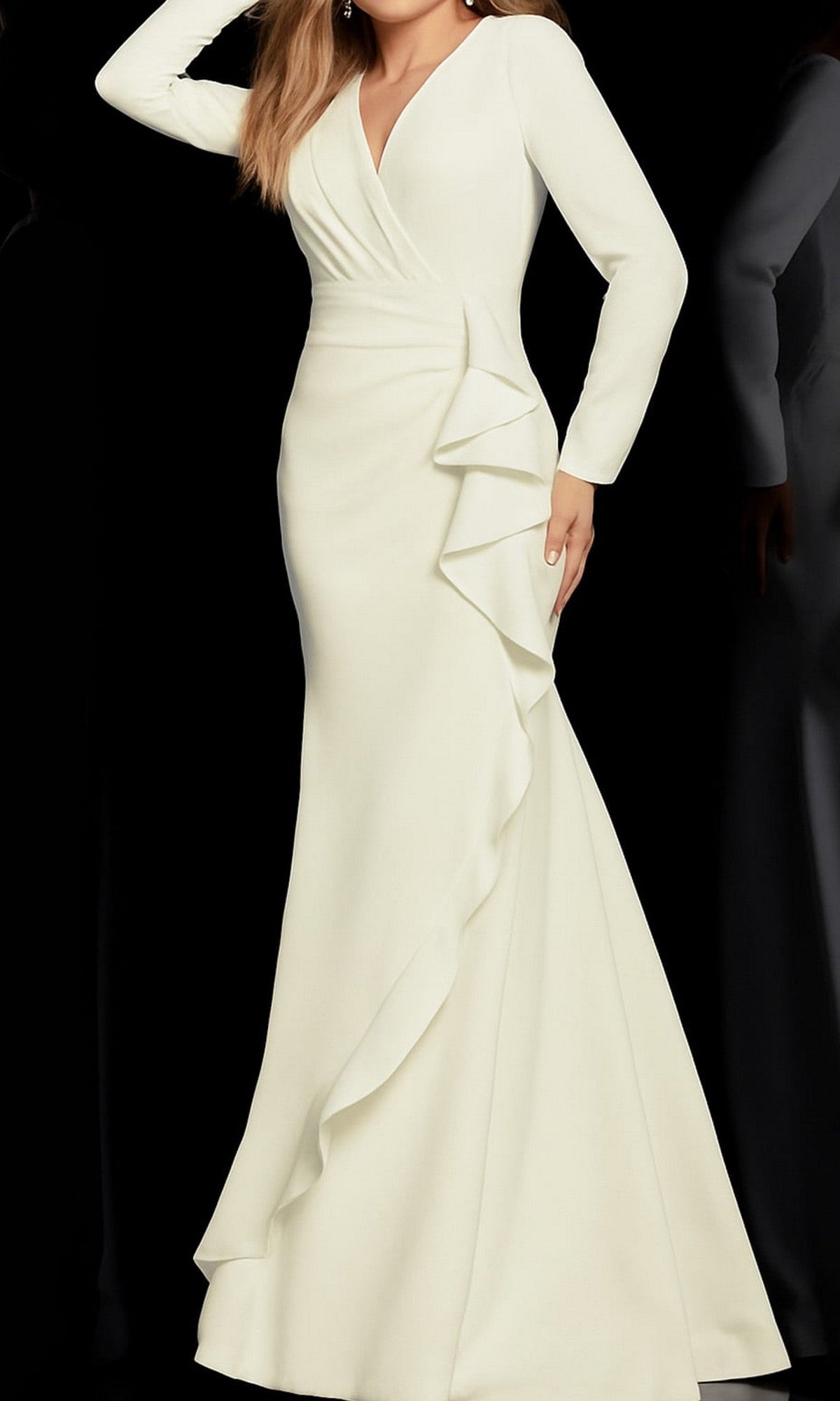 A woman poses against a black background wearing the Jovani 06995 long-sleeve formal designer dress in ivory, featuring a floor-length silhouette, fitted bodice, v-neckline, and asymmetrical ruffle detail along the skirt.