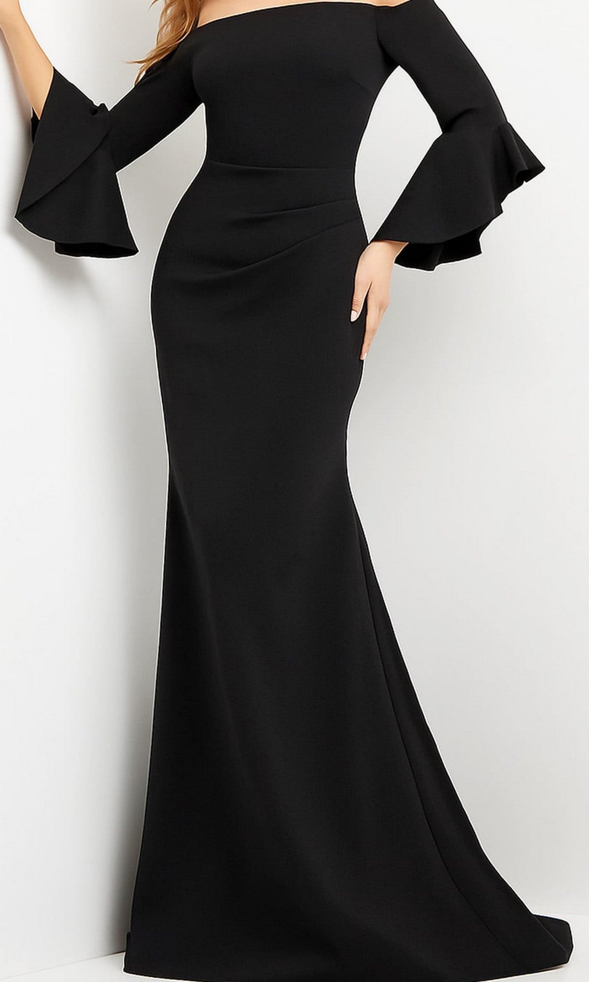 A woman wears the Jovani 07065 Bell-Sleeve Designer Evening Gown in black, featuring a long, off-the-shoulder silhouette with flared, ruffled sleeves, as she stands against a plain light background.