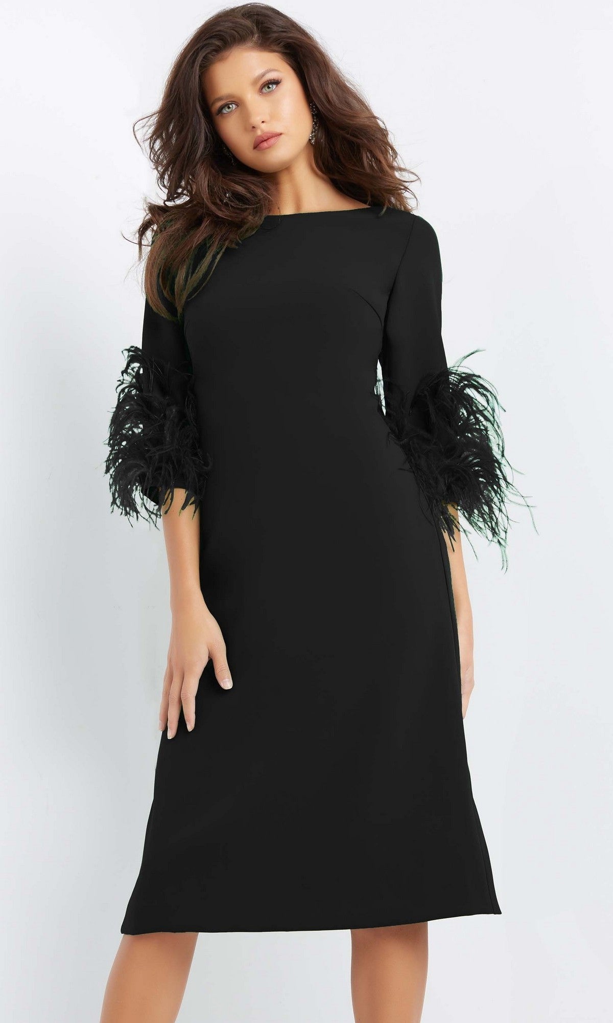 A woman wearing the Jovani 07341 Short Wedding Guest Dress in black, featuring a fitted sheath silhouette with feathered sleeve detailing, stands against a plain white background.
