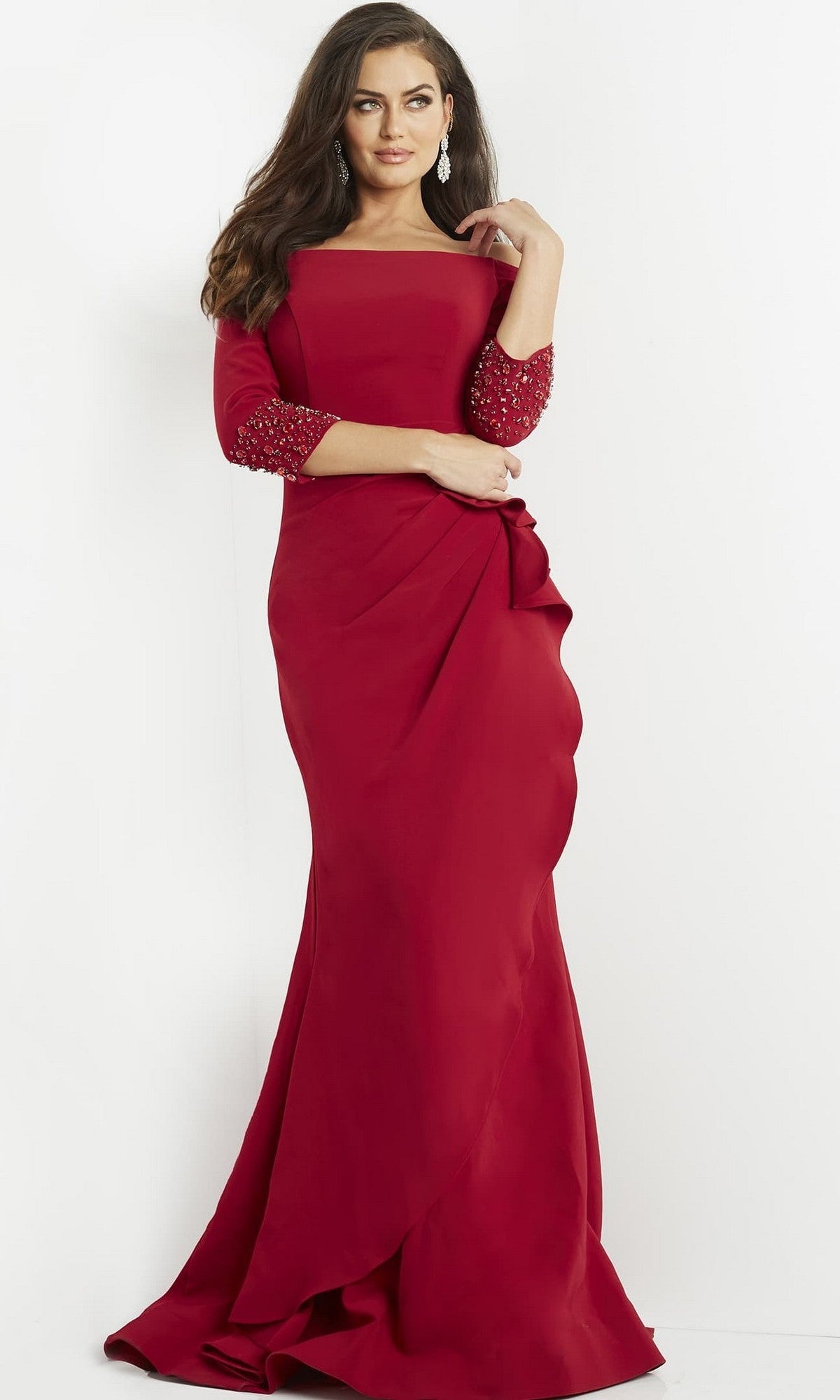 A woman wearing the Jovani 08699 long formal dress, a fitted red gown featuring embellished three-quarter sleeves, stands against a plain white background.