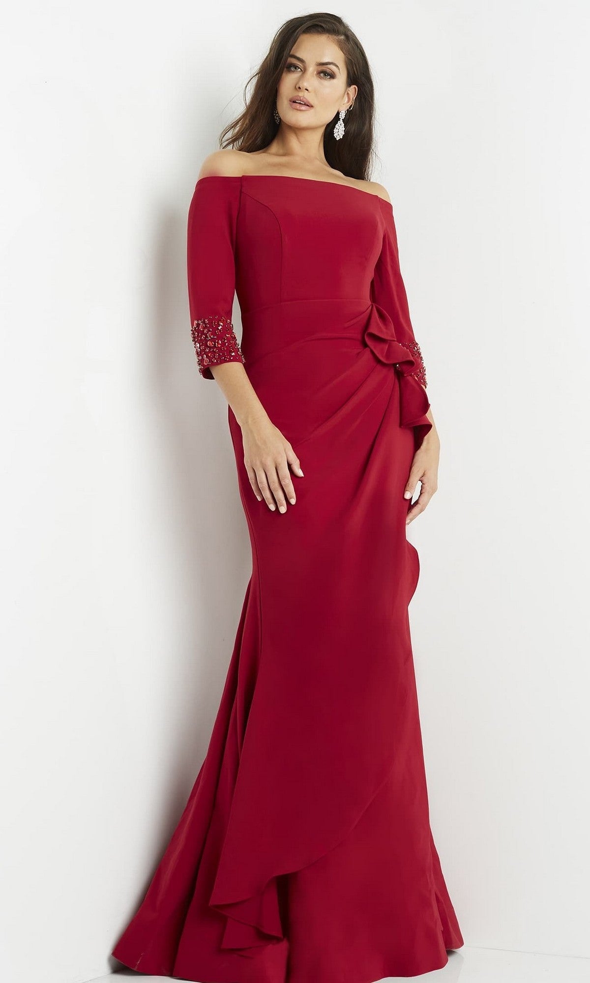 A woman stands against a white background wearing the Jovani 08699 Long Formal Dress in cranberry—a floor-length, off-the-shoulder gown with three-quarter sleeves and decorative details.