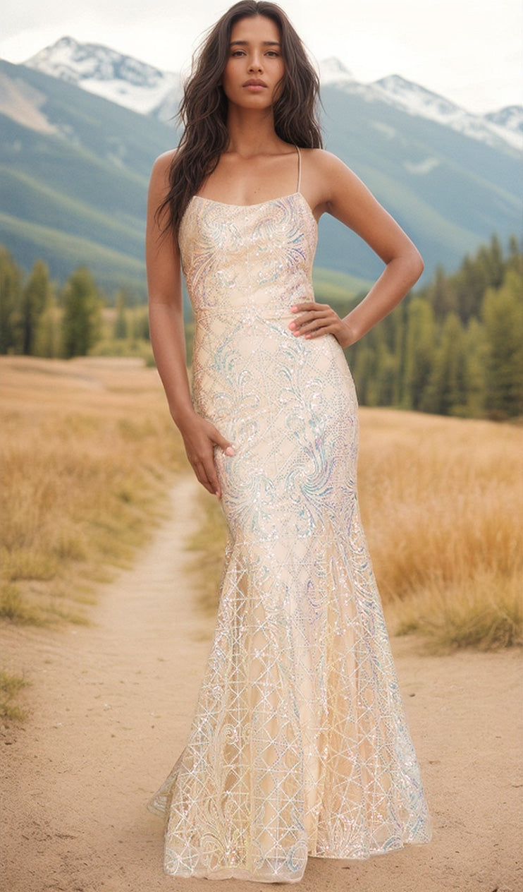 A woman wearing the Iridescent Long Embellished Prom Dress 6116 stands on a dirt path, with grassy fields and mountains in the background.