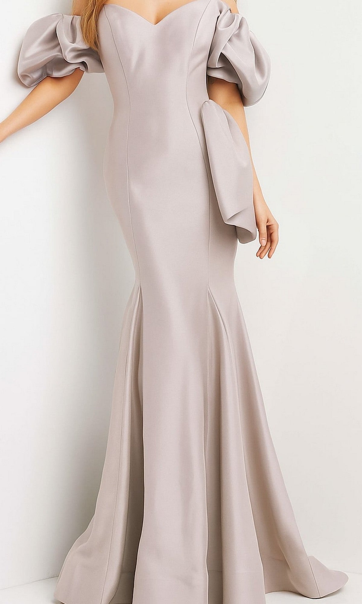 A person wearing the Jovani Puff-Sleeve Long Mermaid Prom Dress 09031 in taupe, featuring puffed off-the-shoulder sleeves and a fitted bodice, stands against a plain background.