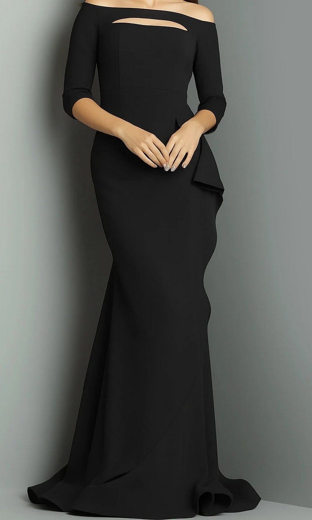 A woman wearing a black, floor-length Long Formal Dress (Jovani 09623) with off-shoulder neckline and three-quarter sleeves stands against a plain background, hands folded at the waist.