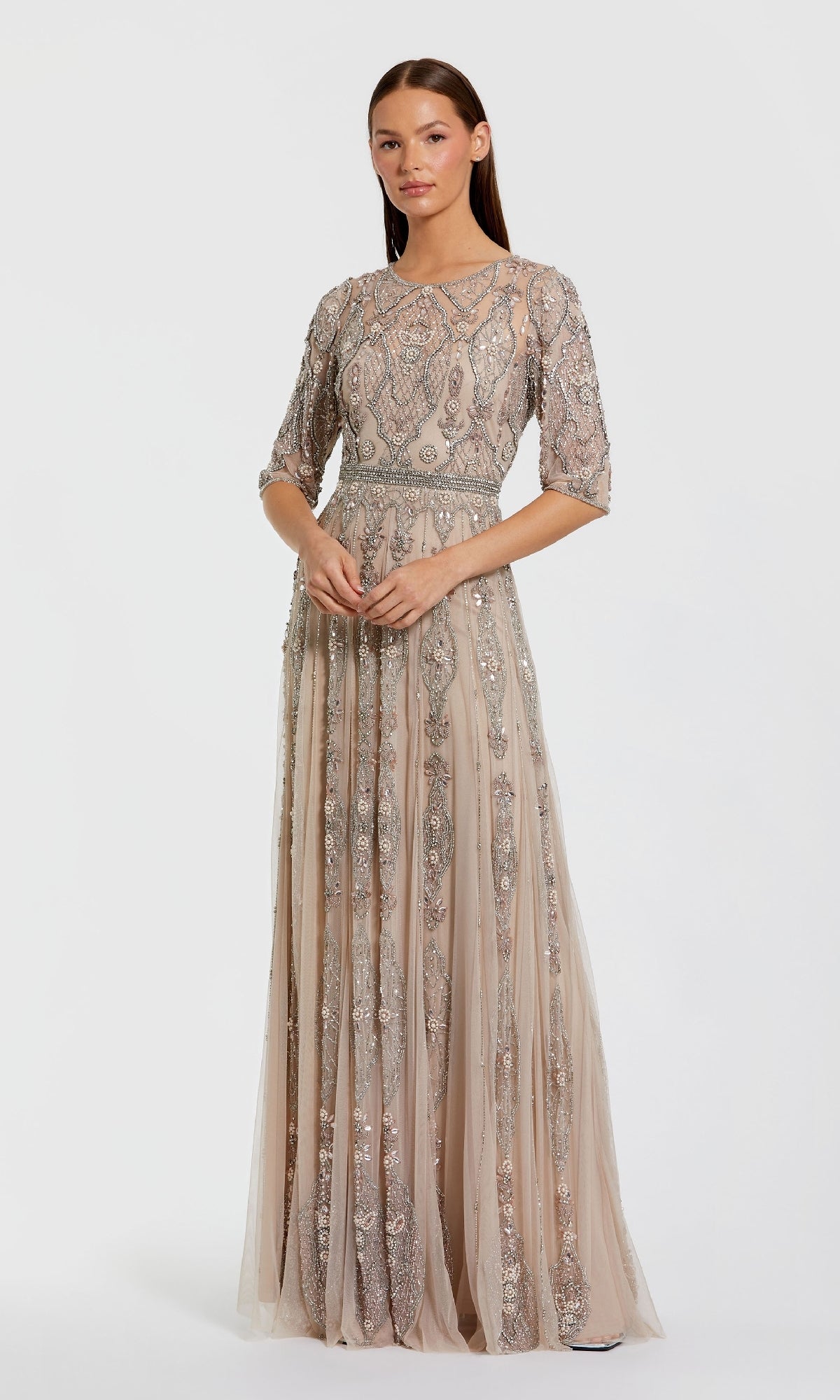 A woman stands wearing the Mac Duggal 10115 Hand-Beaded Lilac Formal Dress, featuring intricate beading, half sleeves, a fitted bodice, and a floor-length skirt.