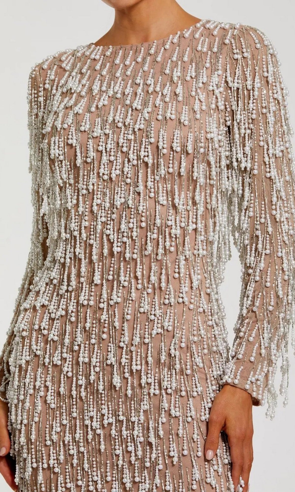 A person wearing the Mac Duggal 10120 midi wedding guest dress, featuring nude long sleeves and dense white bead and sequin embellishments with elegant pearl-beaded fringes arranged in vertical patterns.