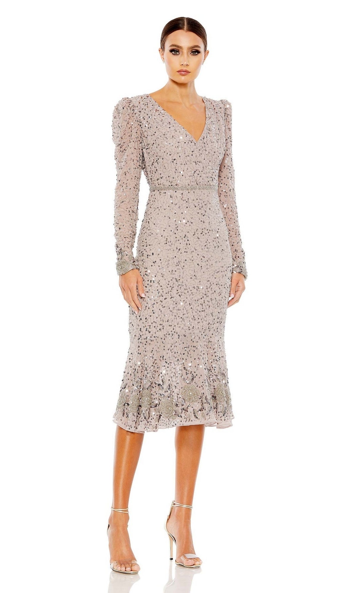 A woman stands against a white background wearing the Mac Duggal 10740, a light mauve long sleeve sequin wedding guest dress with a V-neckline, paired with silver heels.