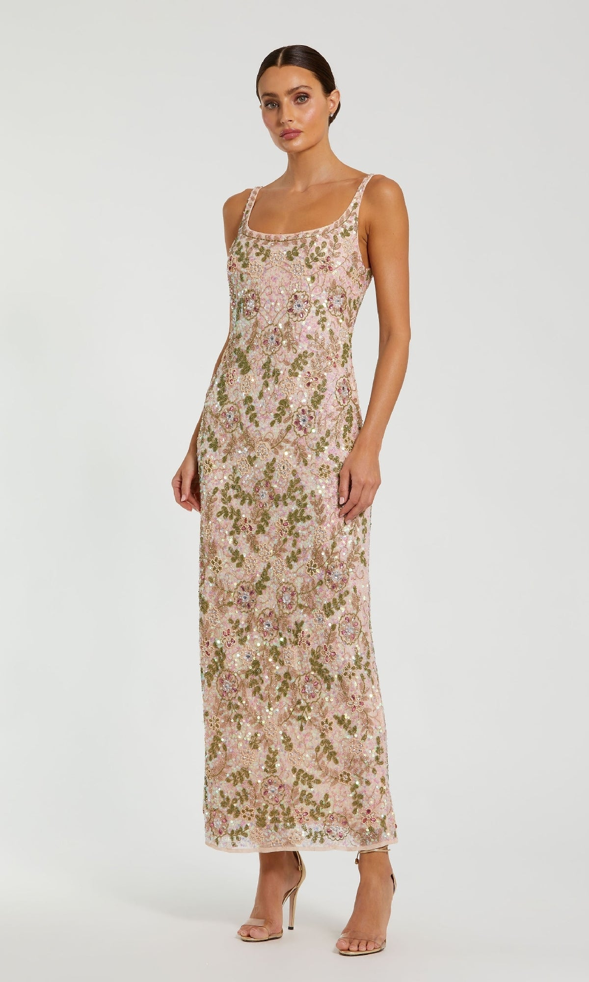 Woman in a Mac Duggal 10755 Sequin Formal Dress with back slit, featuring a sleeveless floral-print design, square neckline, pink and gold sequin embellishments, paired with nude high-heeled sandals.
