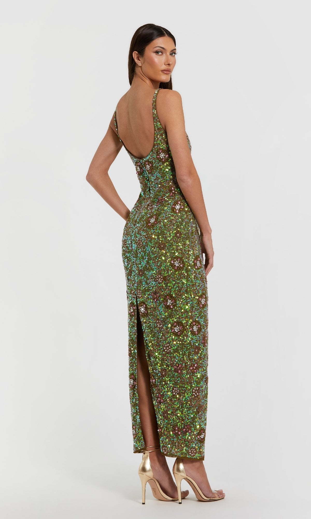 A woman faces away, modeling the Mac Duggal 10755 Sequin Formal Dress with Back Slit and gold high-heeled sandals, set against a plain white background.