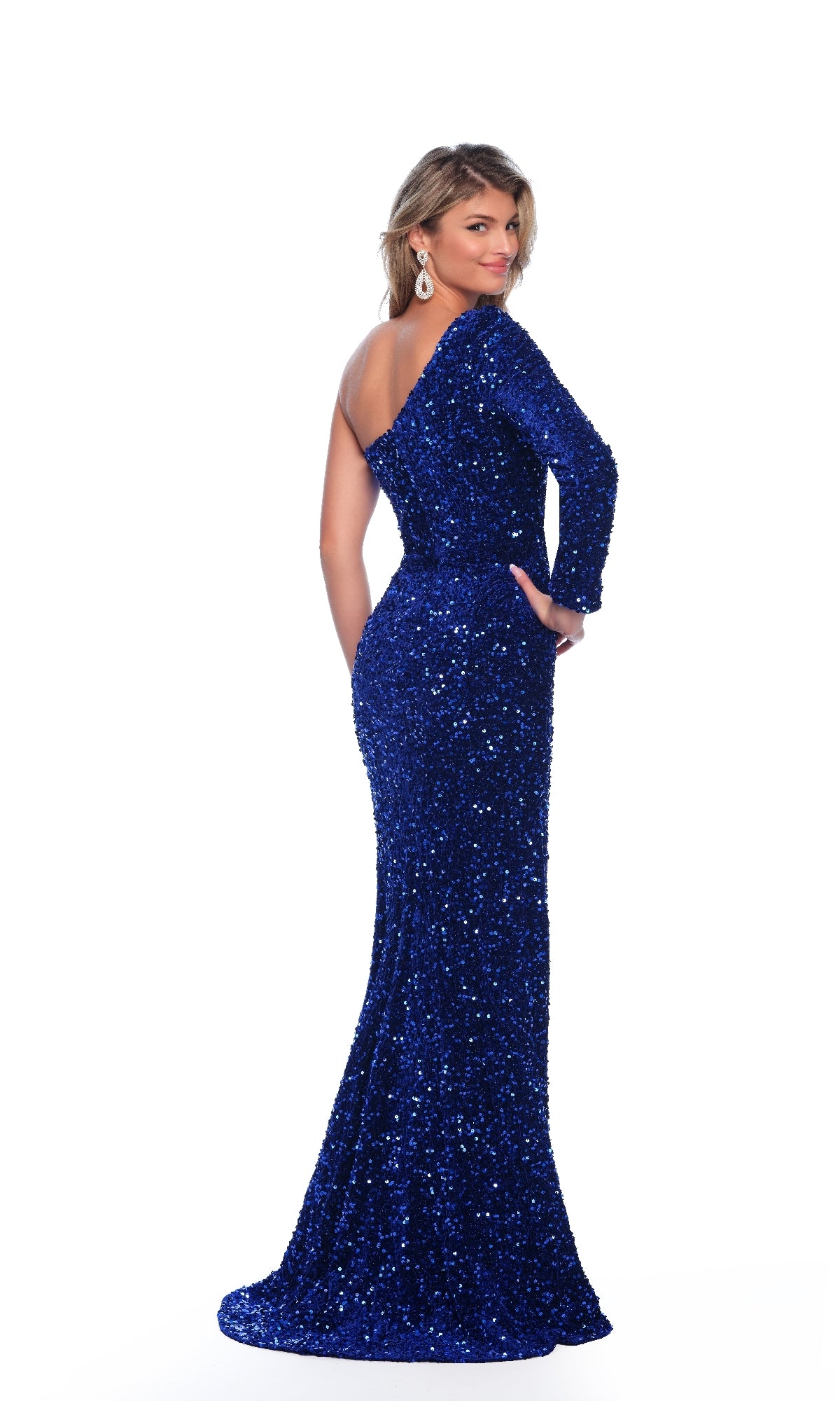 A woman in a royal One-Shoulder Sequin Prom Gown, Dave & Johnny 10892, stands with her back to the camera, looking over her shoulder against a plain white background.