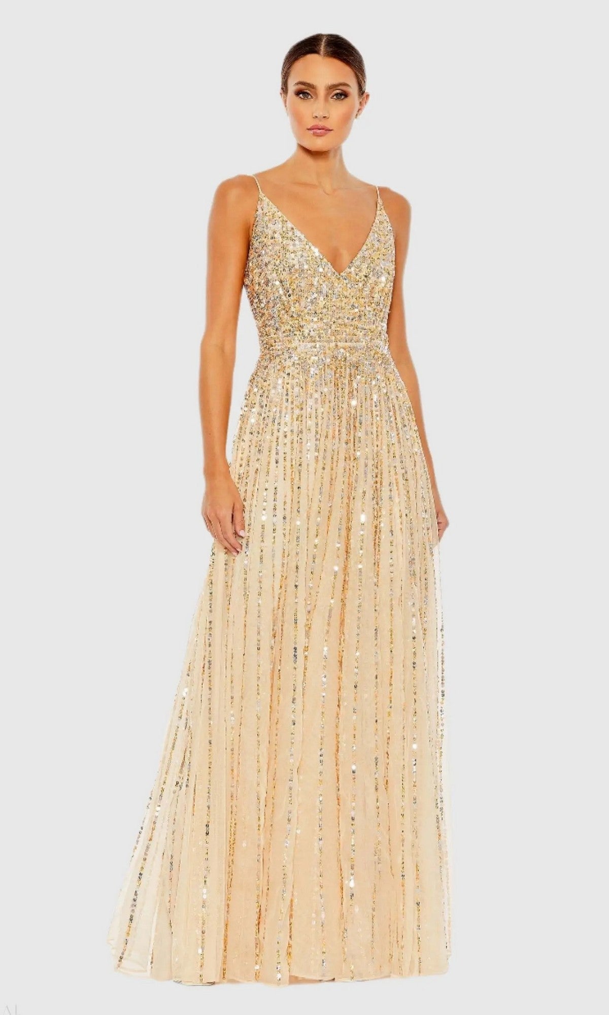 A woman wears the Mac Duggal 10928 long formal dress in nude, a sleeveless gown with gold sequins, V-neckline, and fitted bodice, set against a plain light background.
