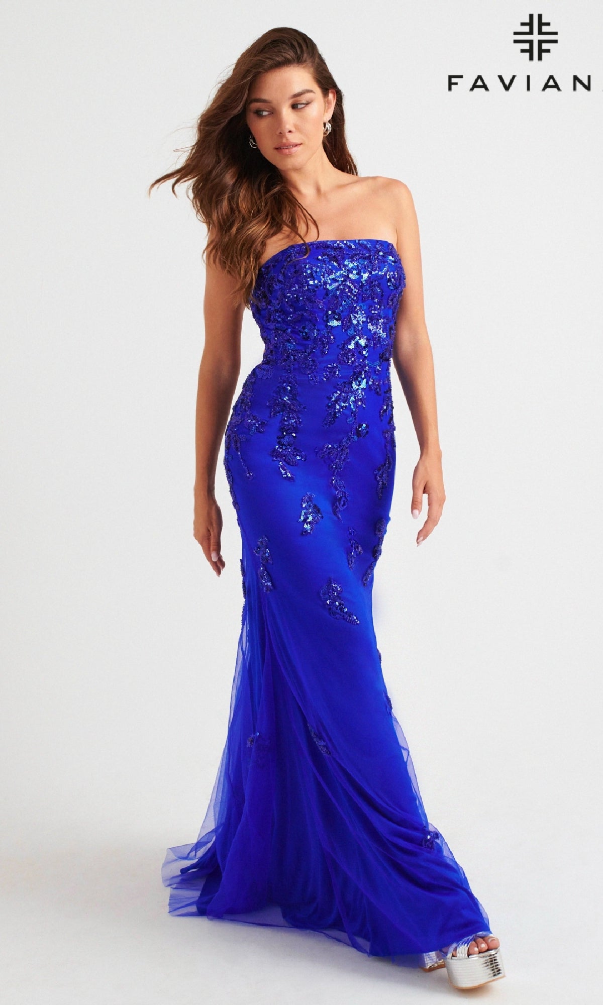 A woman models the Faviana Strapless Long Beaded Prom Dress 11004 in royal blue with sequin details, standing against a white background. The Faviana logo appears in the top right corner.