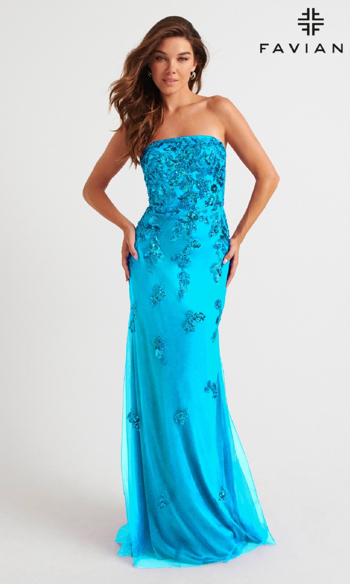 A woman models the Faviana Strapless Long Beaded Prom Dress 11004 in bright blue with floral embellishments, posing before a plain white background. The