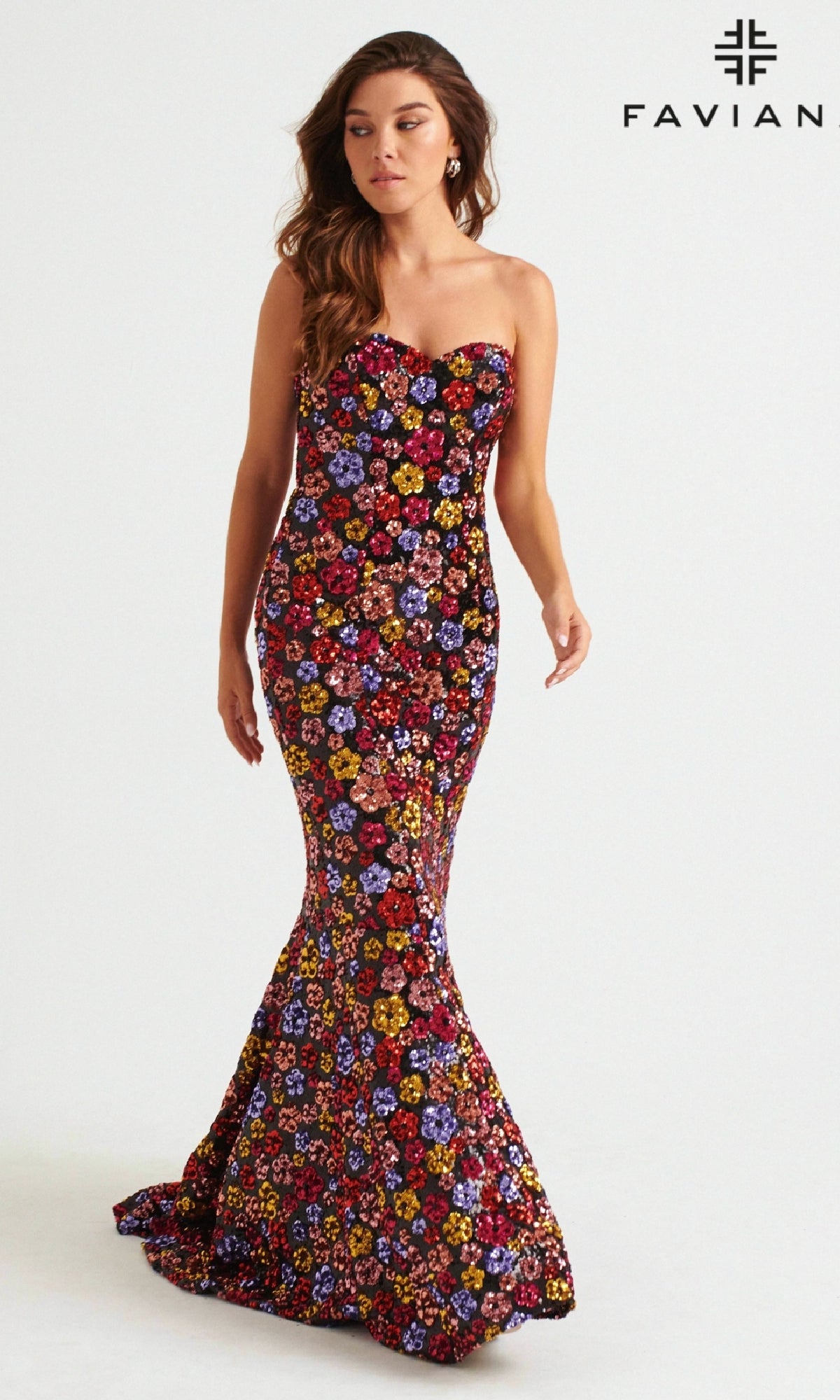 A woman models the Faviana Long Strapless Floral Prom Dress 11036, featuring colorful floral sequins and a plain backdrop with the FAVIAN logo—a stunning choice for any special occasion.