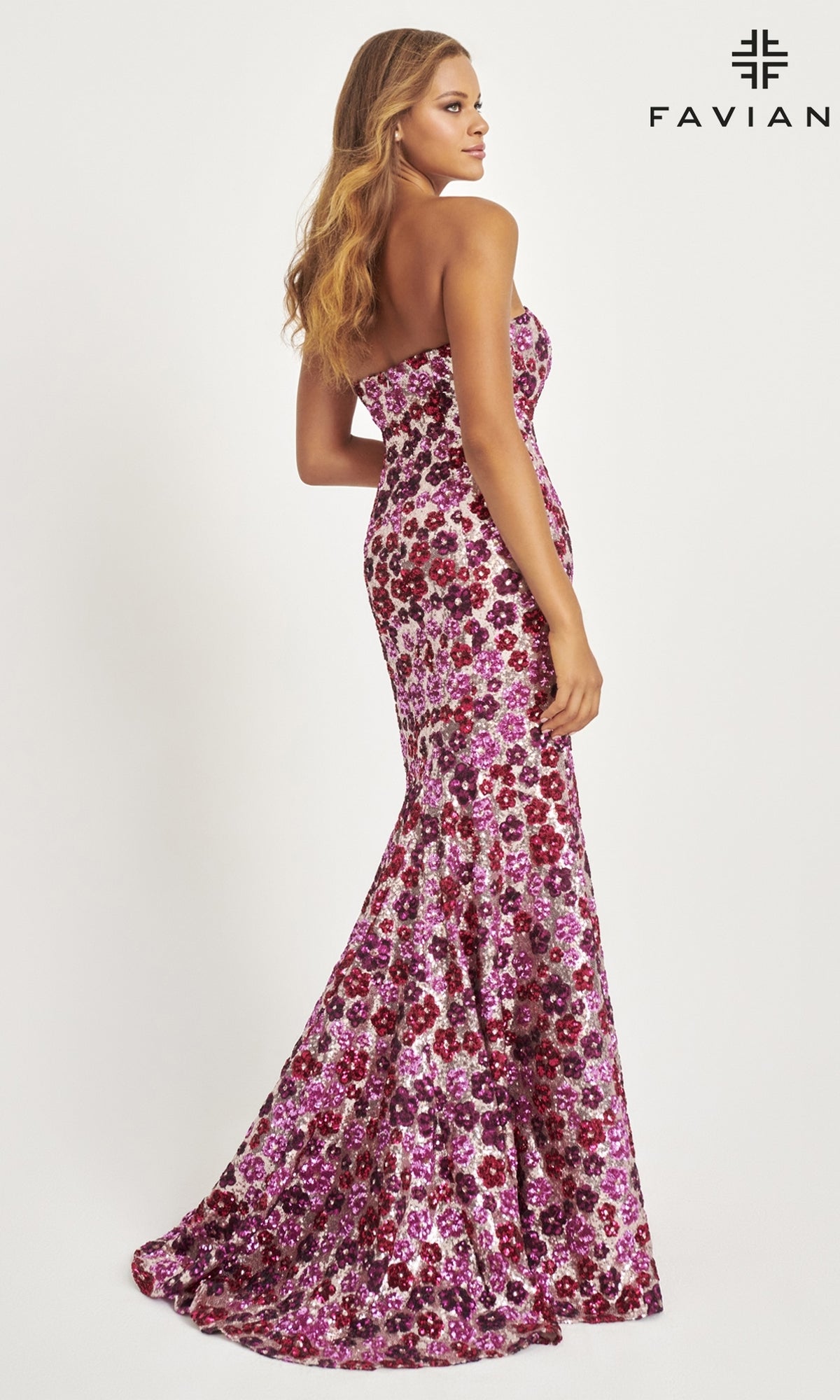 A woman poses in the Faviana Long Strapless Floral Prom Dress 11036, a floor-length gown with a fitted bodice and flared skirt, featuring sequin floral details in magenta and purple, set against a plain white background.