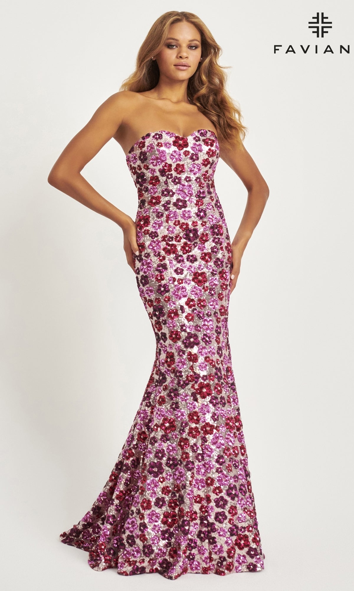 A woman models the Faviana Long Strapless Floral Prom Dress 11036, covered in pink, purple, and red floral sequins, against a plain backdrop with the Faviana logo. This elegant sequin dress is perfect for prom or any special occasion.