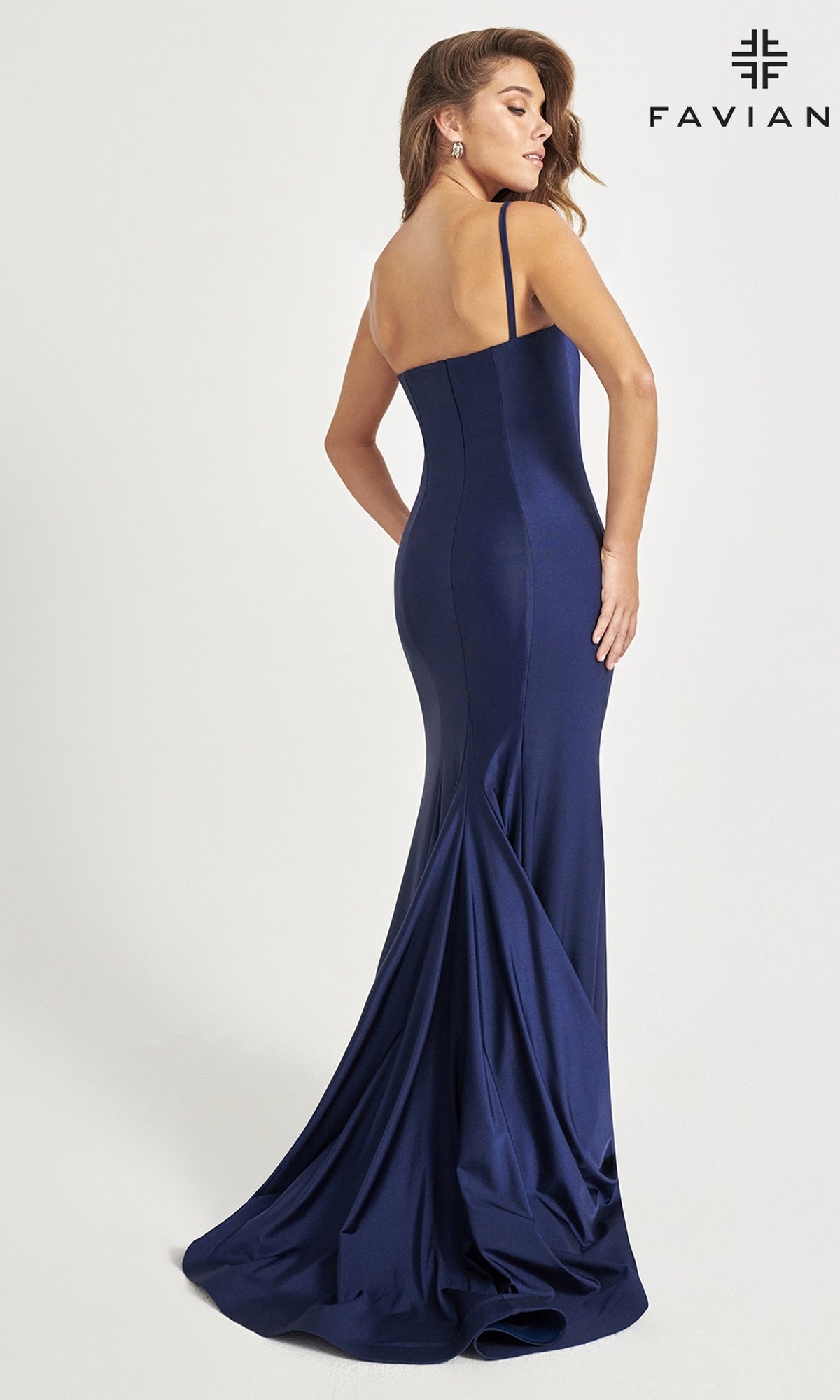 A woman models the fitted, floor-length Faviana One-Shoulder Long Prom Dress 11071 in navy blue, posing with her back slightly turned. The “FAVIANA” logo is displayed in the top right corner.