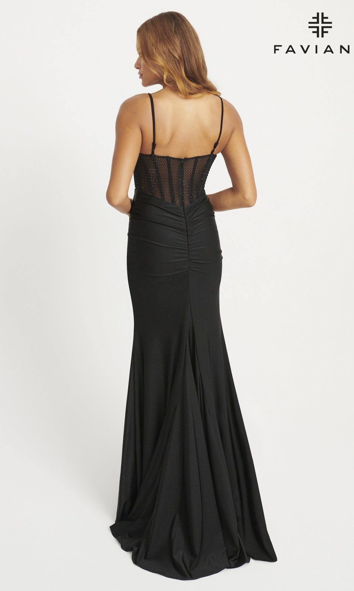 A woman models the Sheer-Waist Long Faviana Prom Dress 11079, a fitted black gown with thin straps, corset-style waist, and sheer mesh back, standing against a plain white background. The Faviana logo appears in the top right corner.