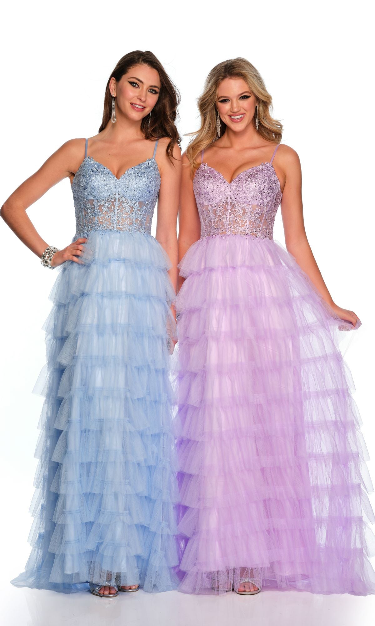 Two women smile at the camera wearing Dave and Johnny Long Tiered Prom Dress 11148, with fitted, embellished bodices; one dress is blue, the other lavender.