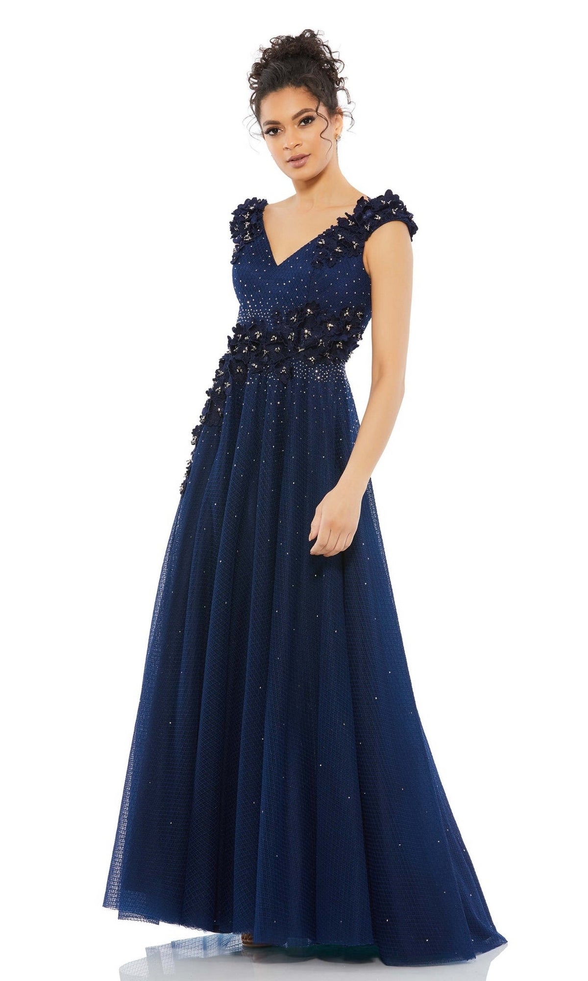 A woman stands against a white background wearing the Mac Duggal V-Neck Midnight Blue Formal Dress 11152, a floor-length gown featuring embroidered floral appliques and beaded embellishments.