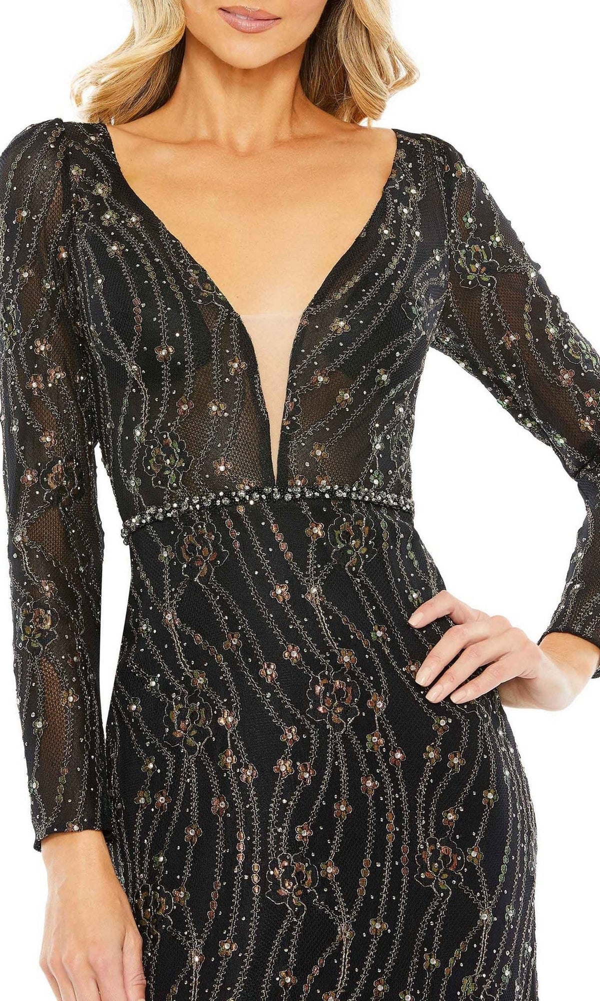 A woman wearing the Long Formal Dress 11159 by Mac Duggal—a black, long-sleeve evening gown with a deep V-neck and sequin embellishments—stands with one hand on her hip.