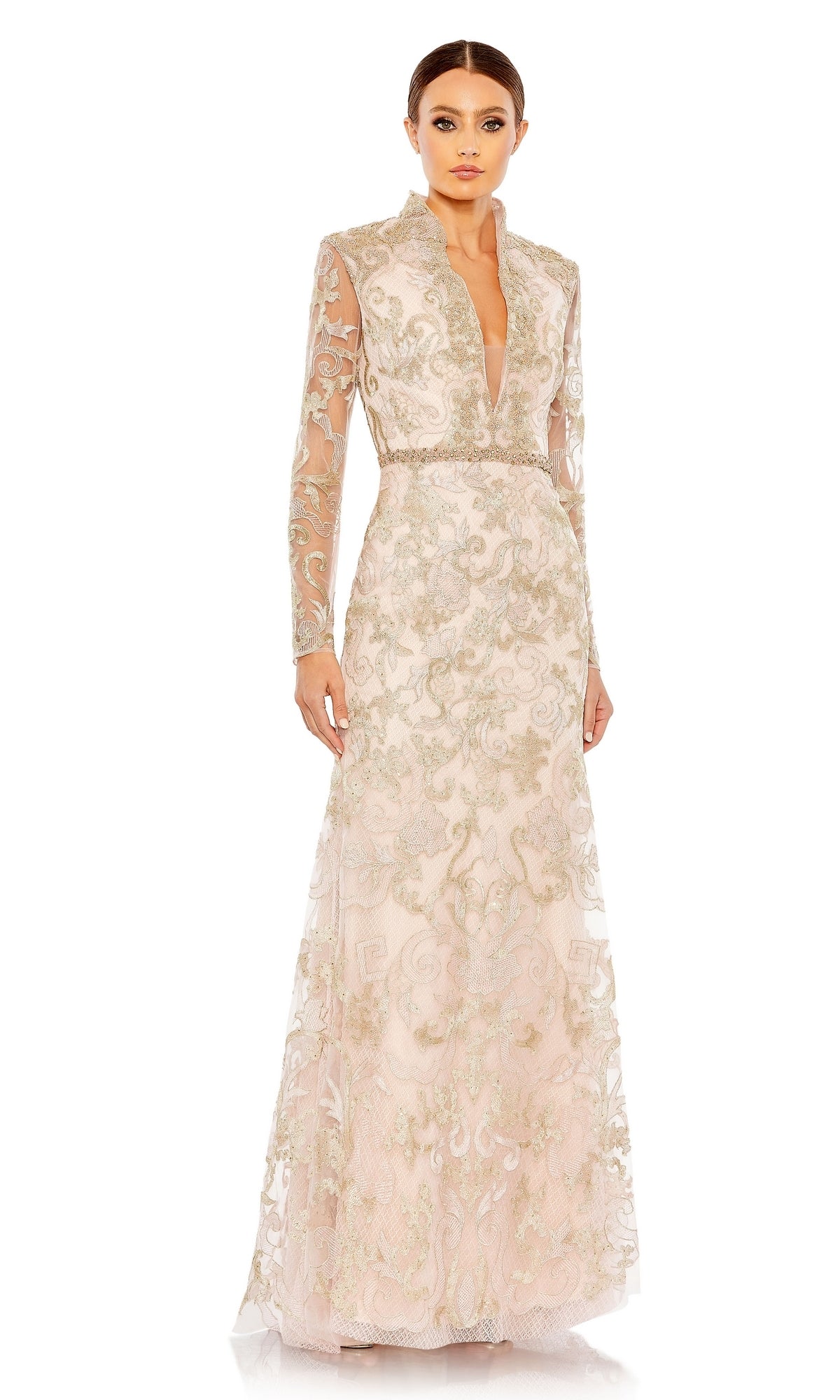 A woman stands against a plain white background wearing the Mac Duggal 11165 Long Sleeve Lace Formal Gown, a vintage-style floor-length dress with gold embroidery and a plunging neckline.