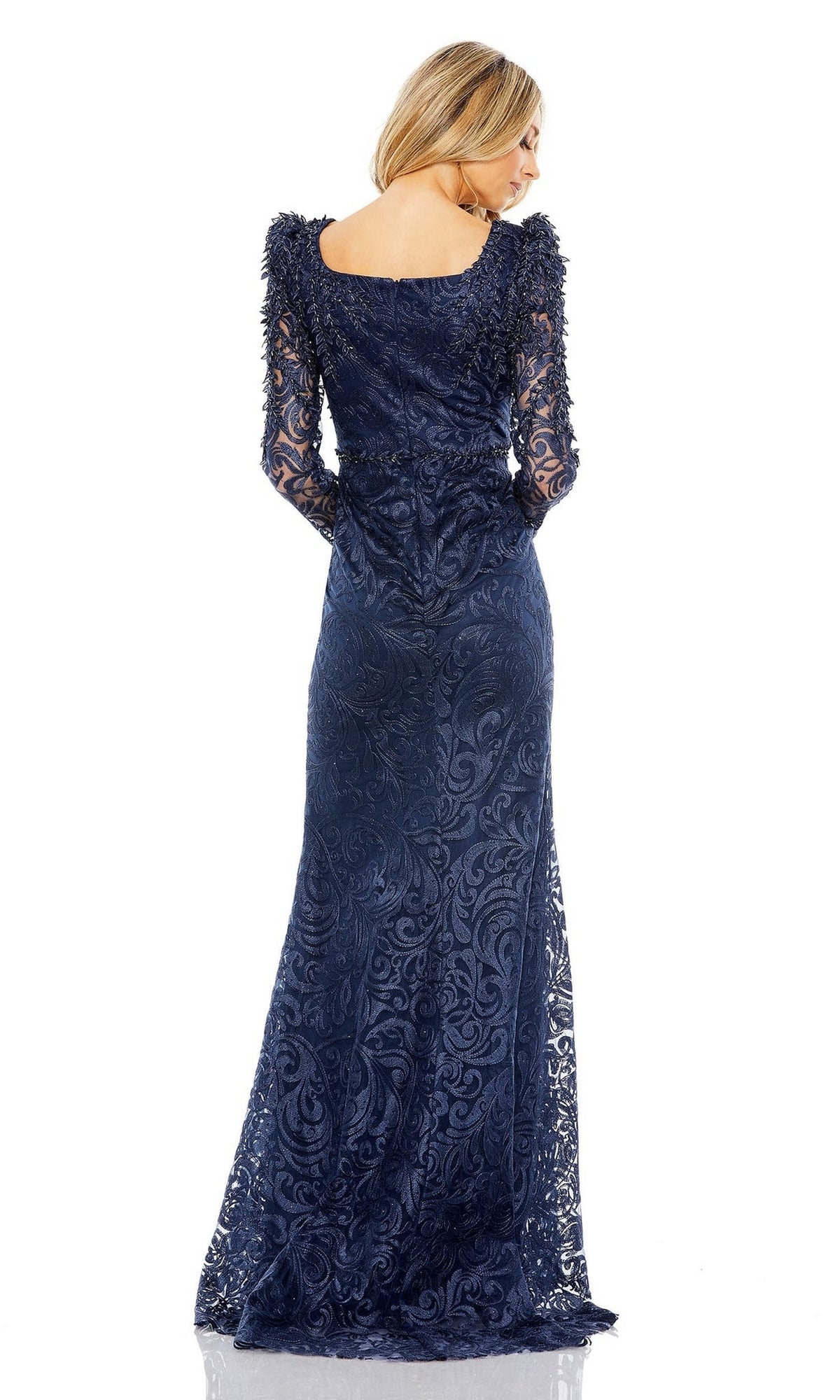 A woman models the Mac Duggal 11187, a long sleeve navy blue lace formal gown, facing away to showcase the elegant back details of this floor-length mother of the bride dress.