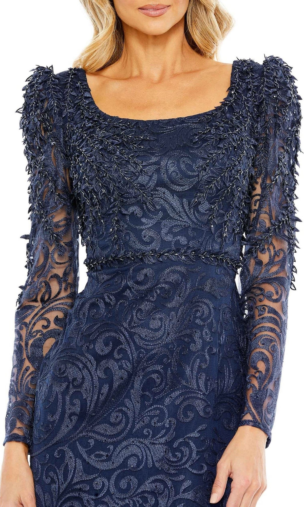 A woman wears the Mac Duggal 11187 long sleeve navy formal gown, featuring intricate lace and leaf-like textured embellishments on the sleeves and bodice—an ideal choice for an evening event or as a mother of the bride dress.