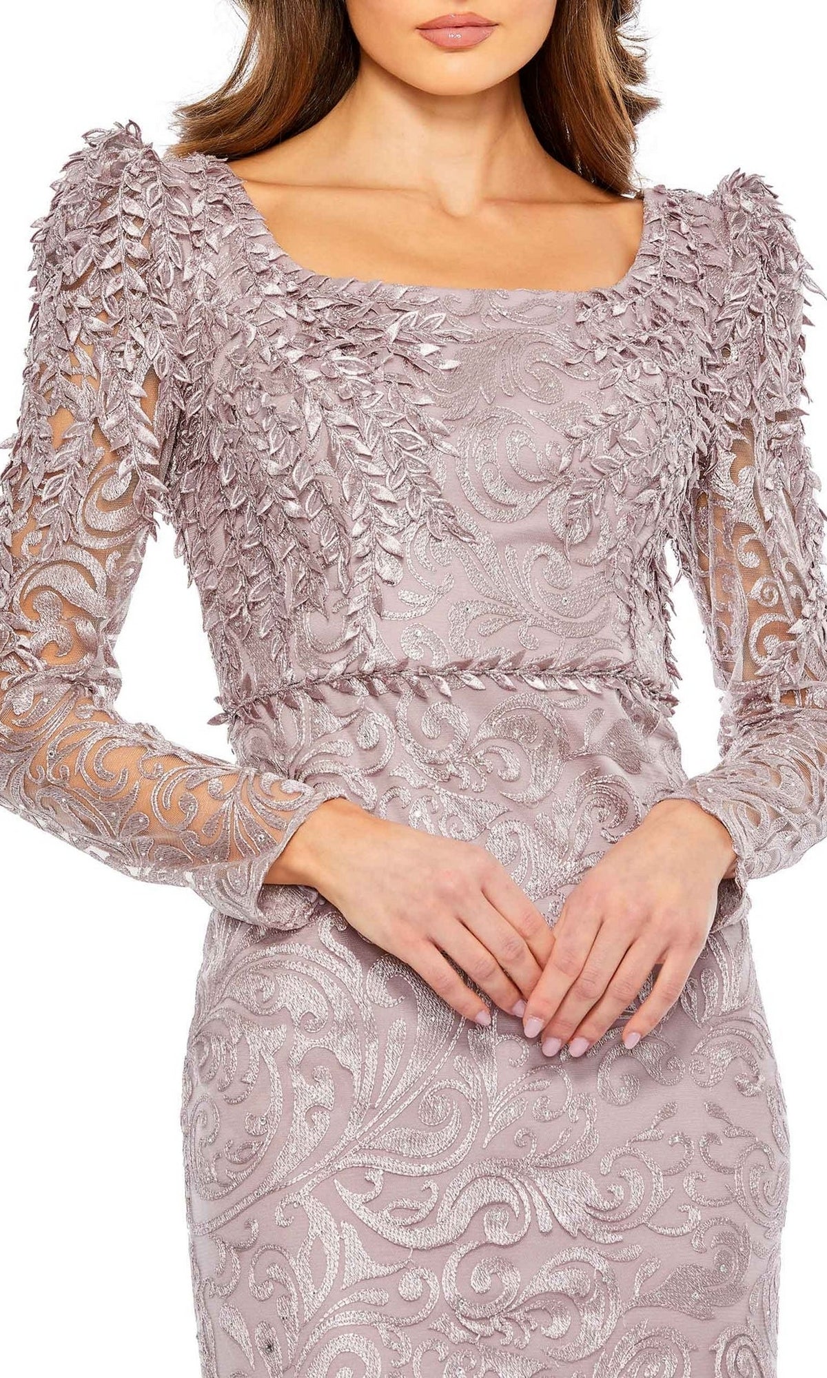 A woman stands with hands clasped, wearing the Mac Duggal 11187 long sleeve formal gown in light purple, featuring elegant leaf-like embellishments.