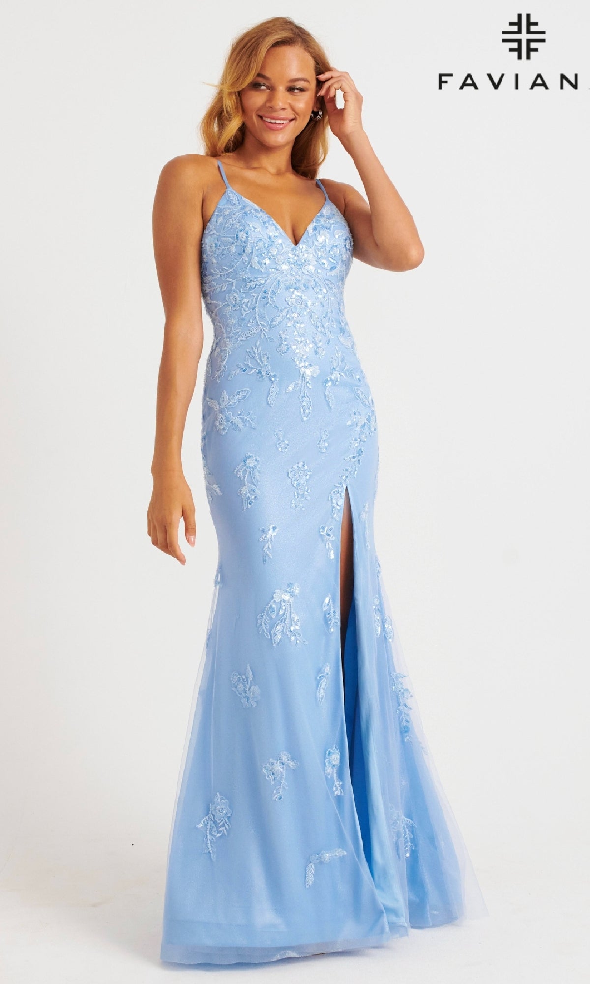Woman wearing Faviana 11229 Shimmer Tulle V-Neck Prom Dress in light blue, featuring thin straps, floral embroidery, and a front slit. Faviana logo appears in the top right corner.