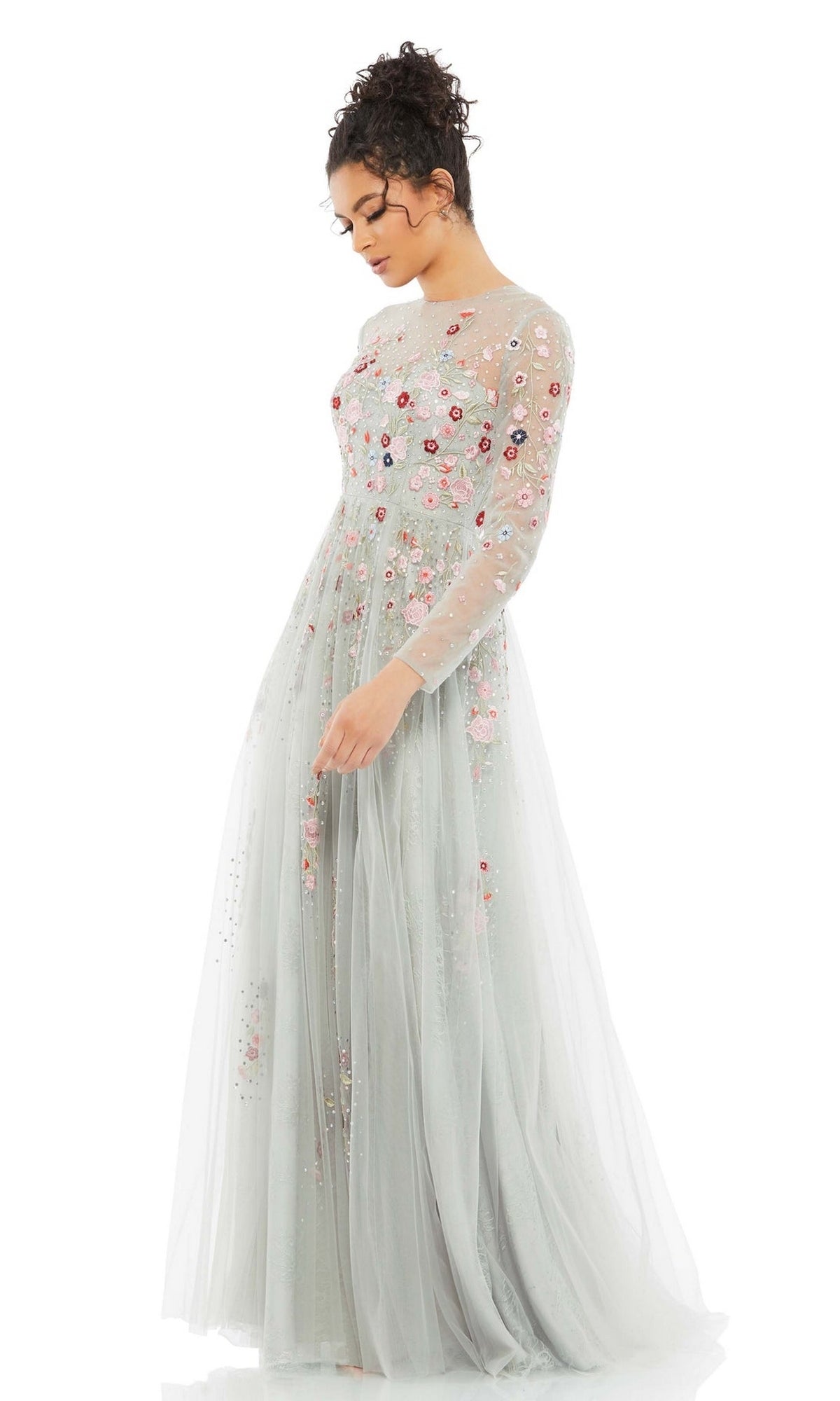 A woman wearing the Long Formal Dress 11241 by Mac Duggal, featuring platinum fabric, floral embroidery, and sheer long sleeves, stands against a white background.