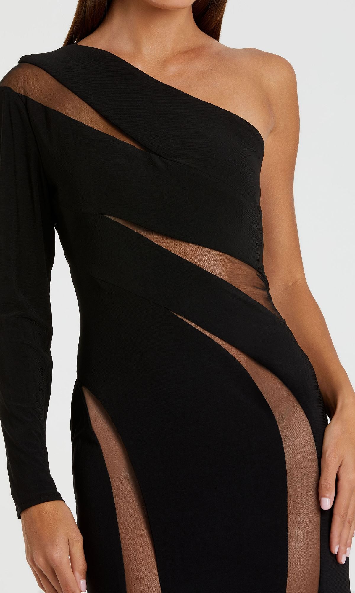 A woman models the Mac Duggal 11311 Cut-Out Long Black Formal Dress, featuring a one-shoulder design with sheer mesh cutouts on the bodice, torso, and leg.