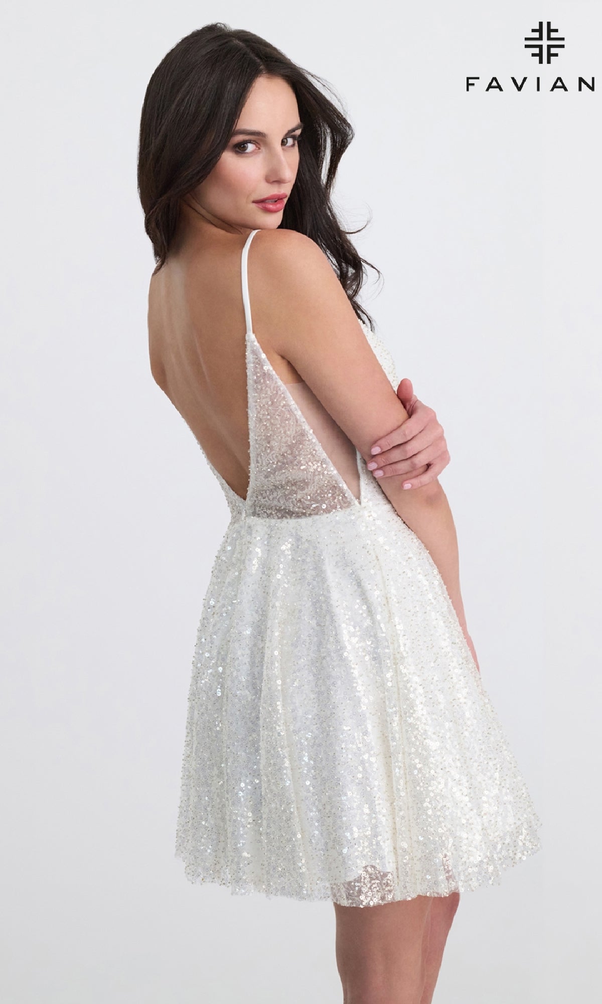 Woman poses over her shoulder in the Faviana 11319 Short A-Line Sequin Hoco Dress, a white, backless cocktail style with thin straps and a flared skirt.