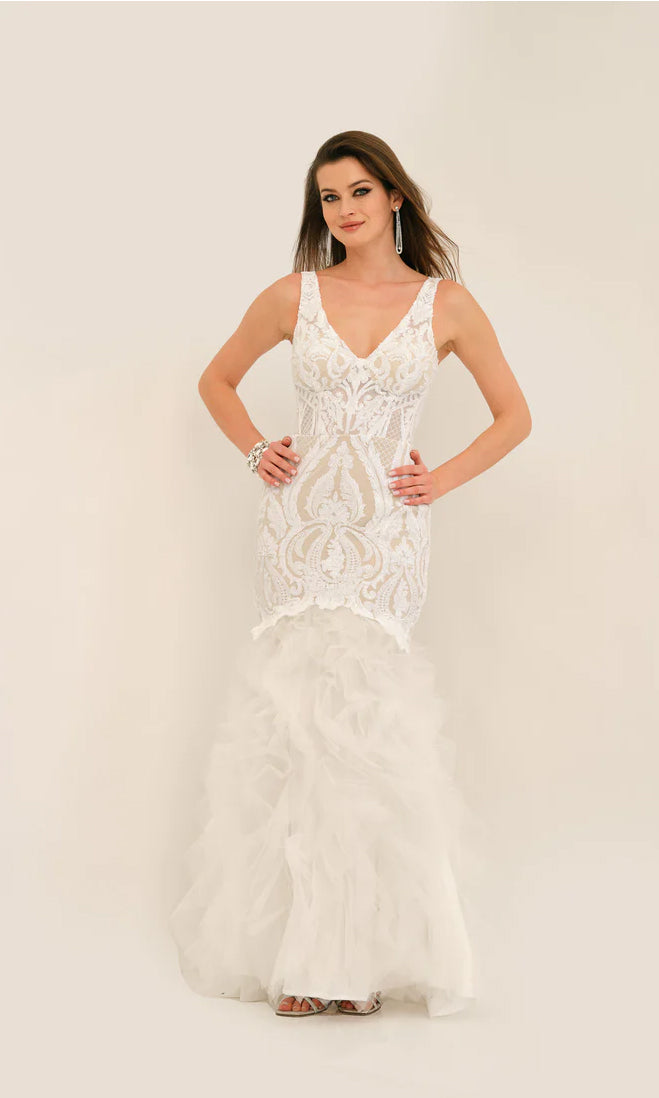 A woman models the Long Formal Dress 11325 by Dave and Johnny—sleeveless, white, with a v-neckline, intricate lace details, and a ruffled tulle skirt—standing against a plain light background.