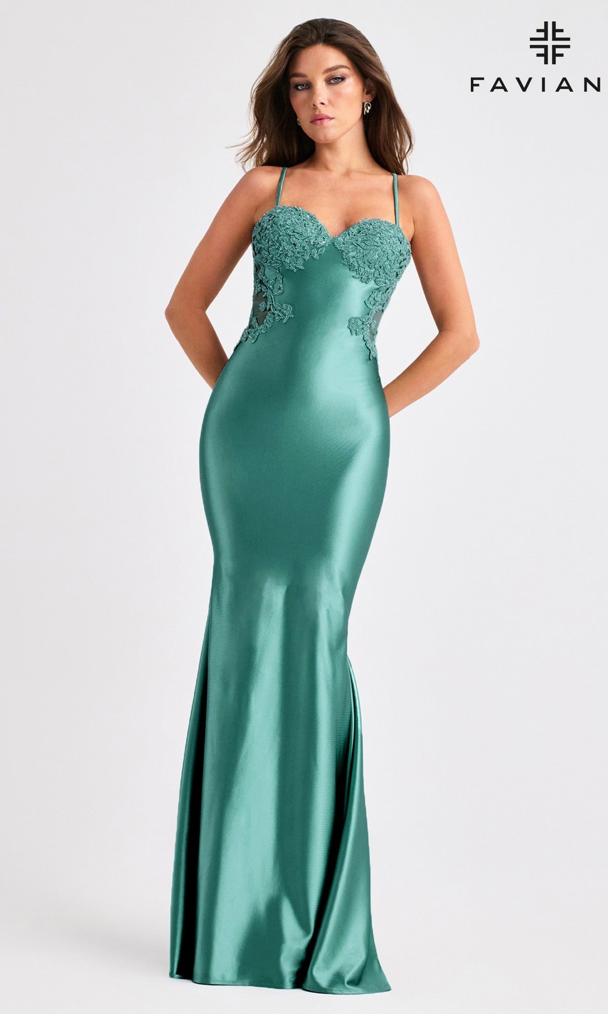 A woman wears the Faviana 11403 long prom dress—a fitted, floor-length teal satin gown with thin straps, open back, and lace bodice—standing against a plain background. The