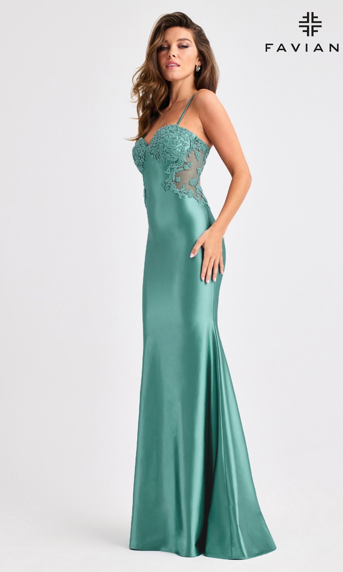 A woman poses in the Long Prom Dress: Faviana 11403, a fitted floor-length teal satin gown with lace details, thin straps, and an elegant open-back design, set against a plain white background with the Faviana logo in the corner.