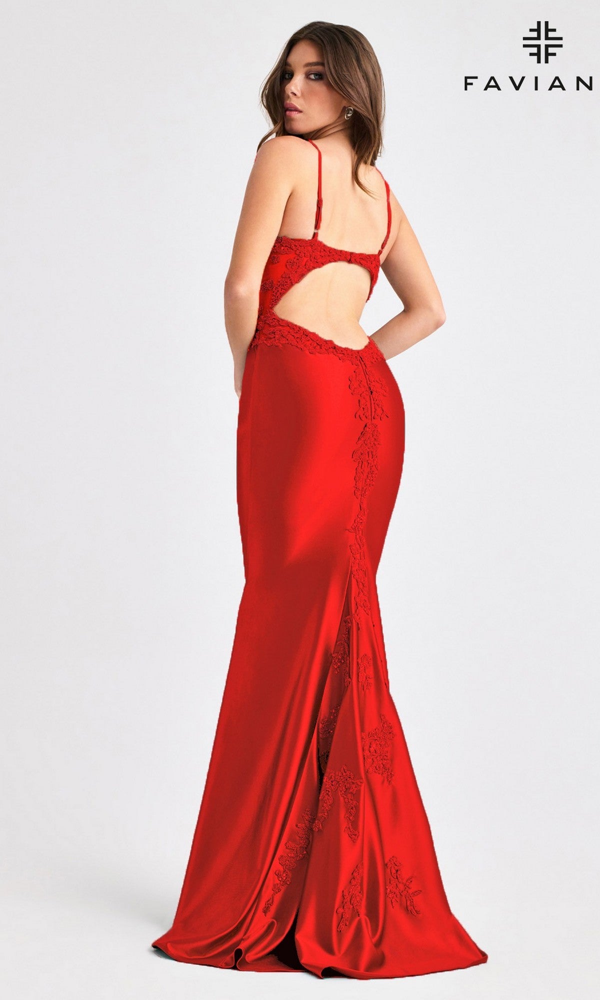 A woman in a fitted, floor-length red prom dress with lace details and open back stands facing away from the camera.