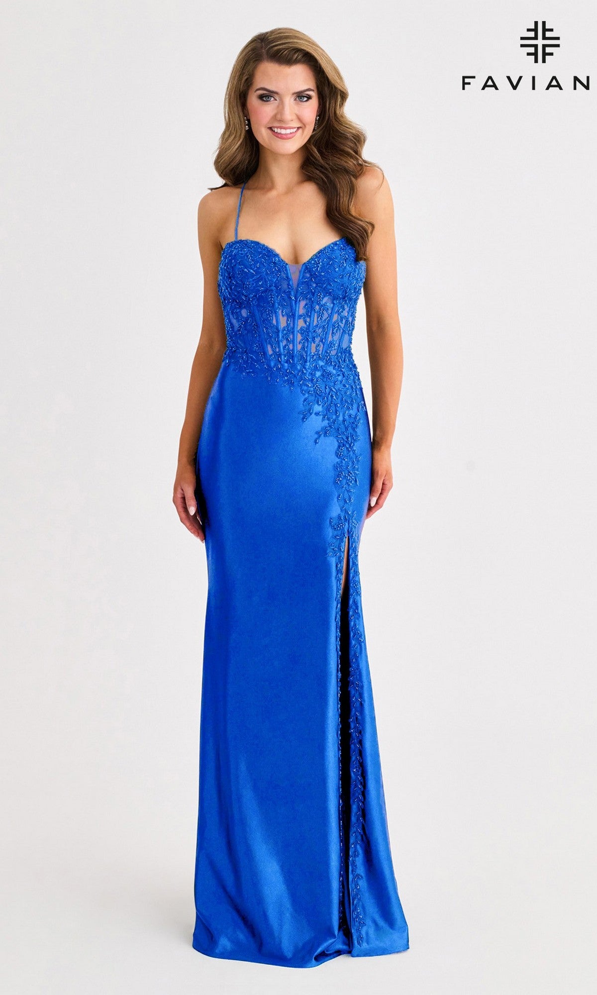 A woman wearing the Faviana 11404 long prom dress in royal blue satin, featuring lace details, a corset bodice, sweetheart neckline, and thigh-high slit stands against a plain background.