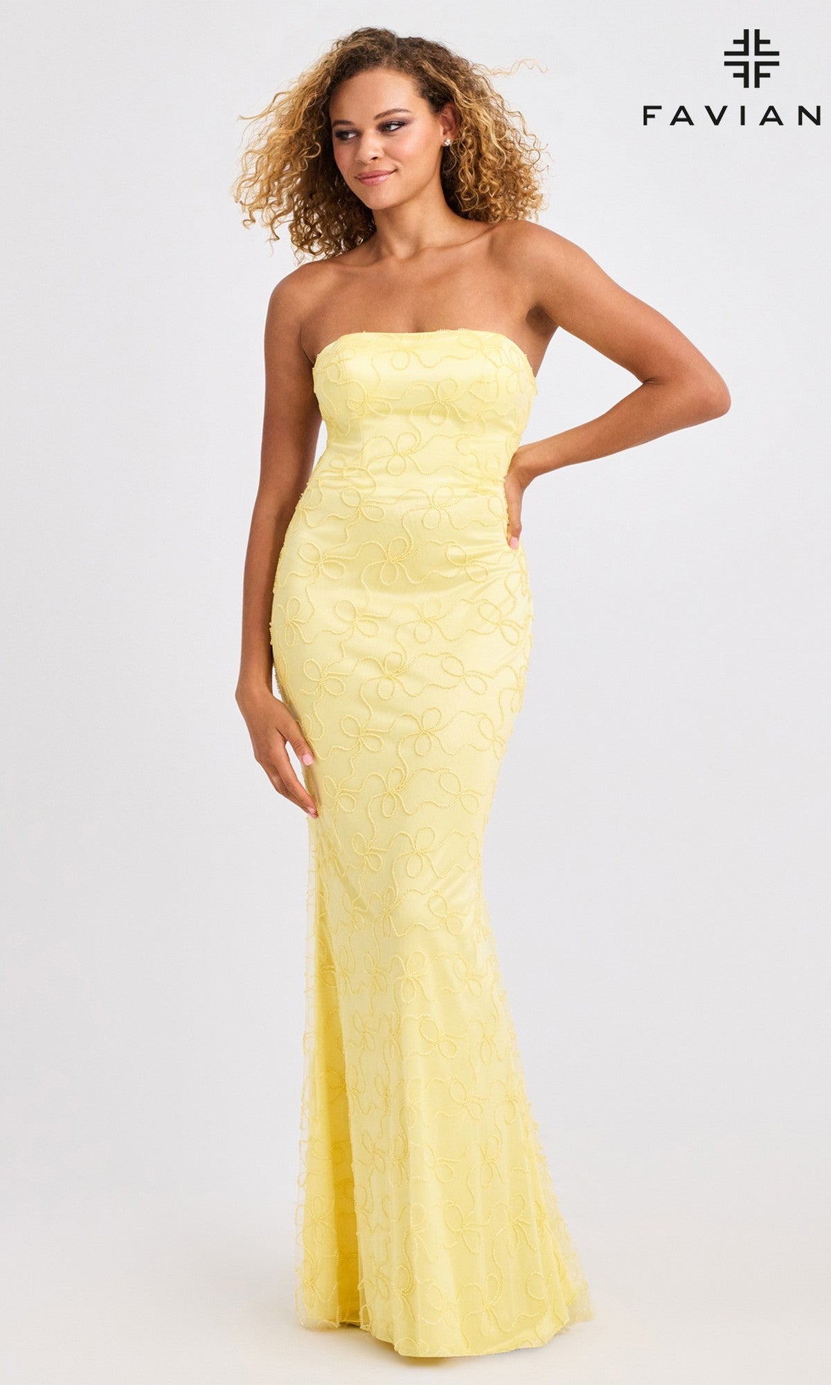 A woman models the Faviana 11416—a strapless, form-fitting yellow long prom dress with a subtle swirl pattern and strappy open back—against a plain background. The Faviana logo appears in the top right corner.