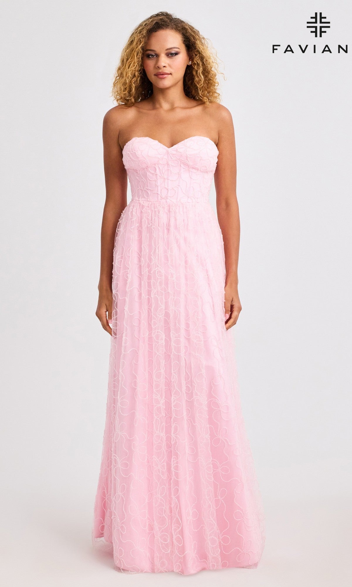 A woman models the Faviana 11418 long prom dress—strapless with a corset bodice and floor-length pink gown featuring a subtle swirl pattern—against a plain background.