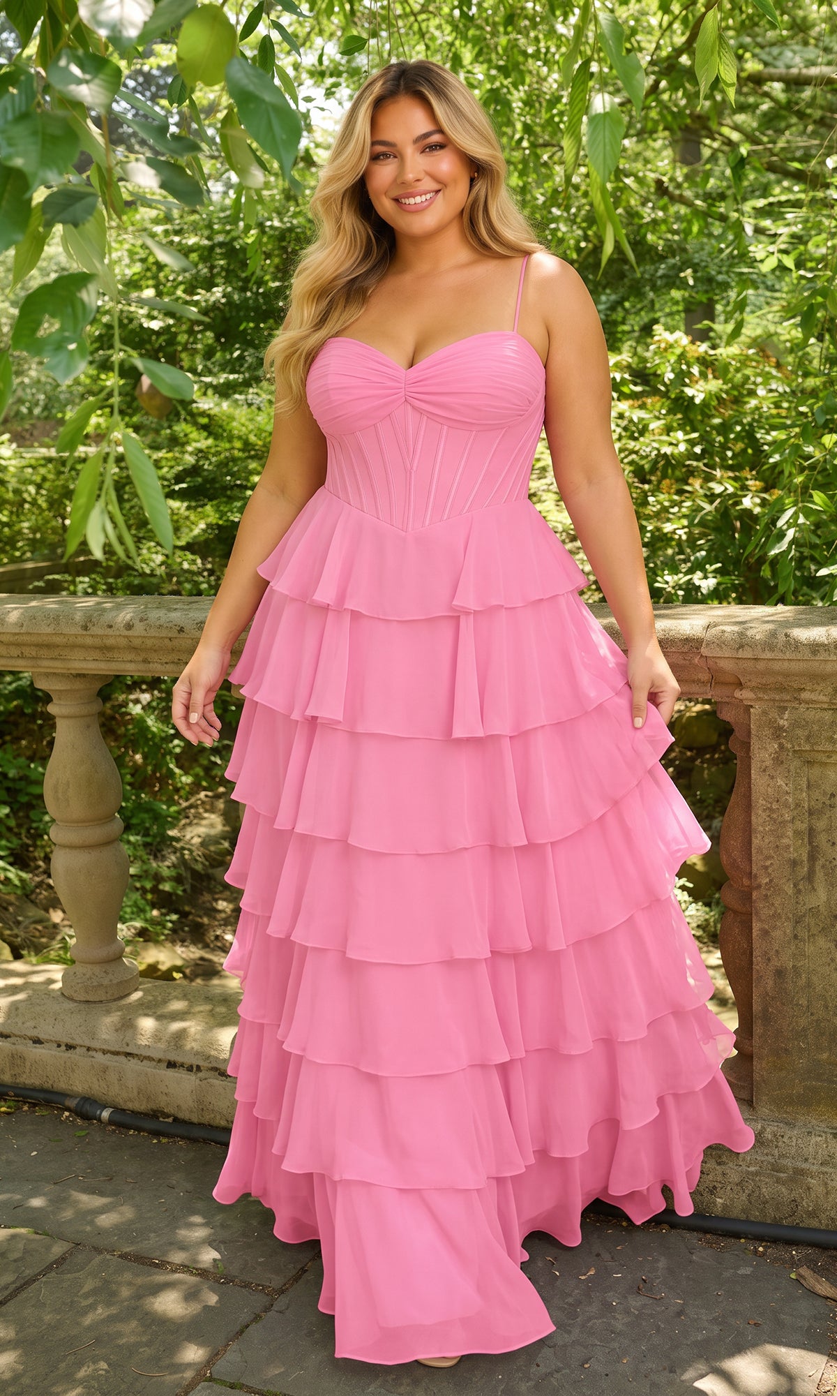 A person wears a cotton candy pink Long Plus-Size Prom Dress: Faviana 11420E, featuring a corset-style bodice and a tiered, chiffon ruffle skirt.