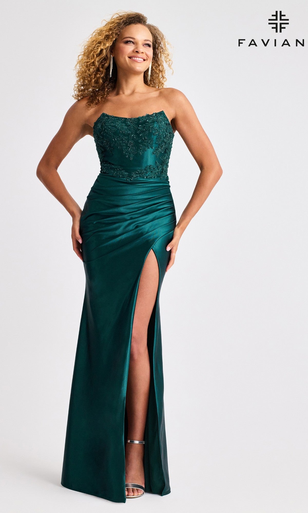 A woman models the Faviana 11429 long prom dress—strapless satin with a beaded bodice and high slit—paired with silver heels, standing against a plain background featuring the Faviana logo in the corner.