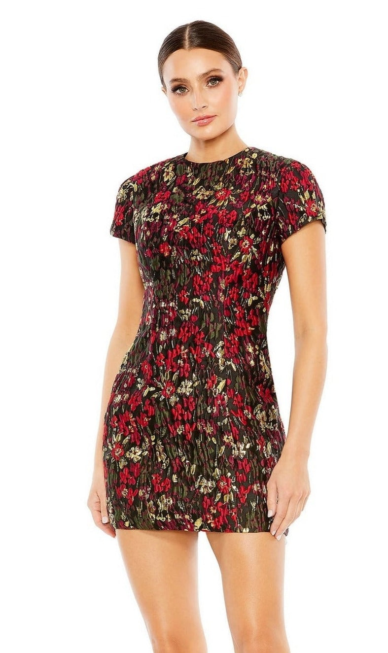 A woman models the Mac Duggal 11613 Short Floral Wedding Guest Dress, a fitted, short-sleeved mini dress in red, green, and black—an elegant choice for parties or as a chic short wedding guest look.